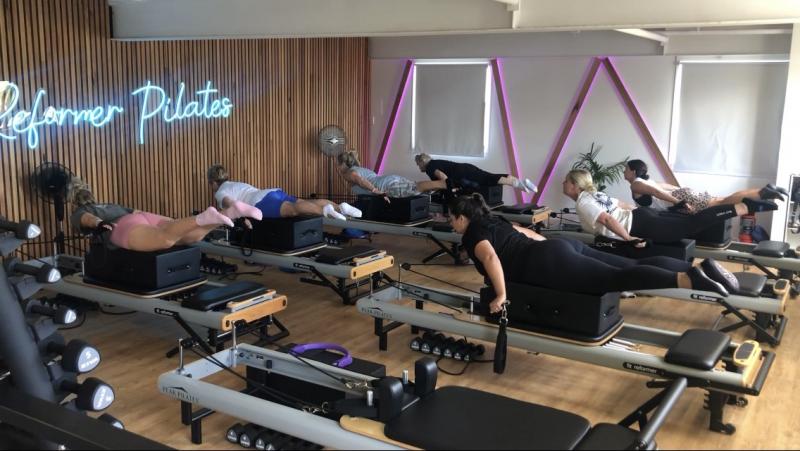 students in plough pose on the reformer pilates machine at Genesis Fitness Port Macquarie